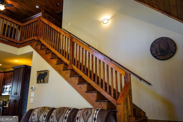 staircase with wooden ceiling, ceiling fan, and a high ceiling