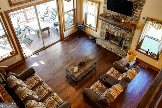 living room featuring a stone fireplace and dark wood-type flooring