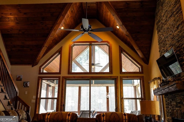 living room with vaulted ceiling with beams, a wealth of natural light, wooden ceiling, and ceiling fan