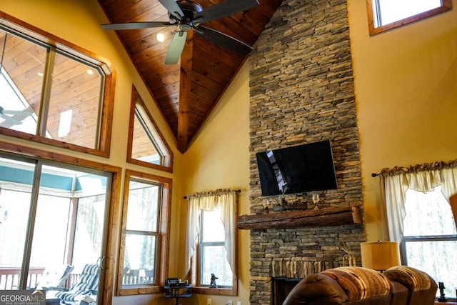 living room featuring lofted ceiling, a stone fireplace, wooden ceiling, and ceiling fan