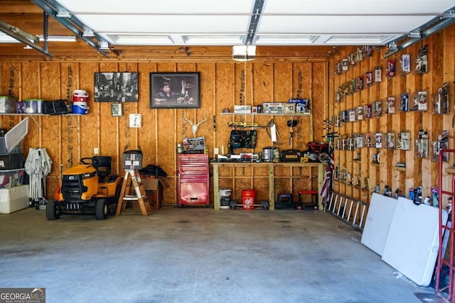 garage featuring a garage door opener, a workshop area, and wood walls