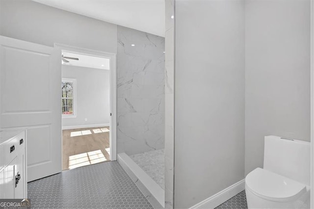 bathroom featuring tiled shower and toilet