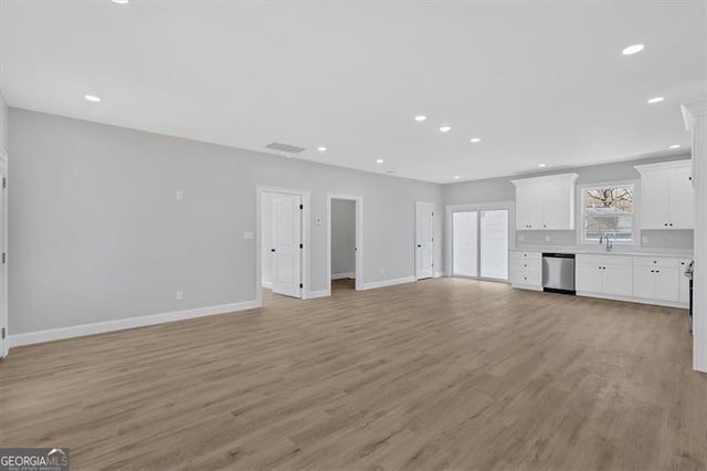 unfurnished living room featuring sink and light hardwood / wood-style flooring