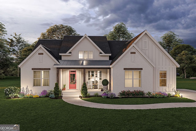 view of front of property featuring brick siding, board and batten siding, a front lawn, and a standing seam roof