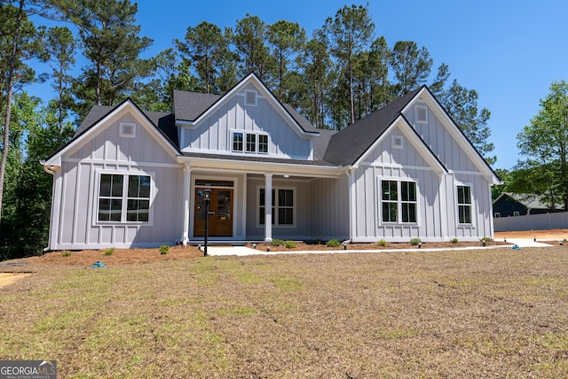 modern inspired farmhouse featuring board and batten siding, a front yard, and a porch