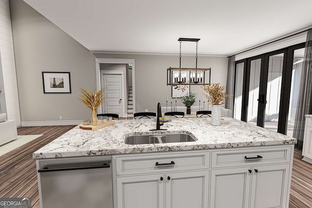 kitchen with a sink, wood finished floors, white cabinetry, light stone countertops, and hanging light fixtures