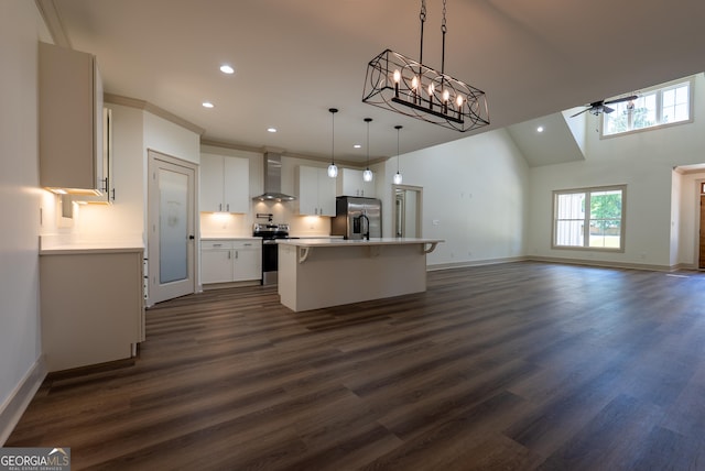 kitchen with appliances with stainless steel finishes, wall chimney range hood, ceiling fan, recessed lighting, and a kitchen island