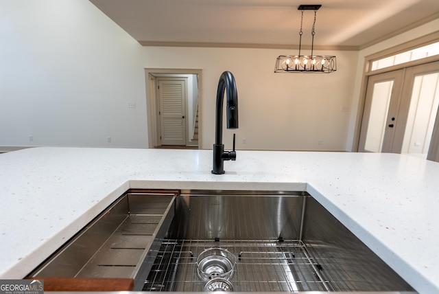 kitchen view of a sink, light stone countertops, and hanging light fixtures