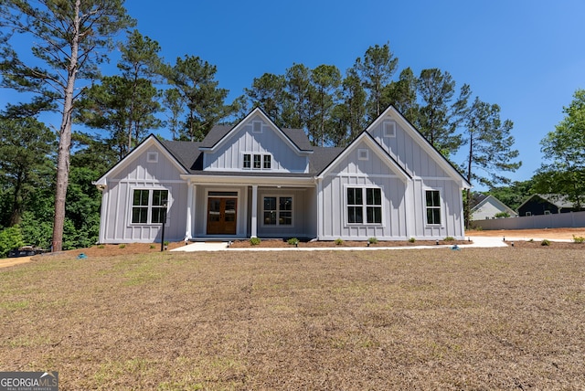 modern inspired farmhouse with board and batten siding, a front yard, and a porch