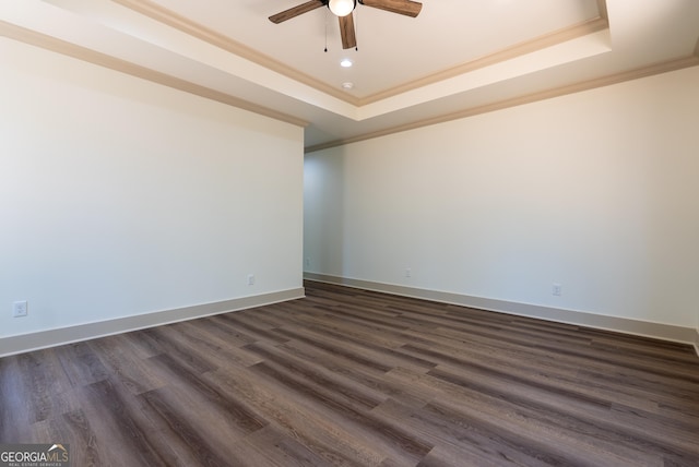 spare room featuring a raised ceiling, crown molding, a ceiling fan, dark wood-style flooring, and baseboards