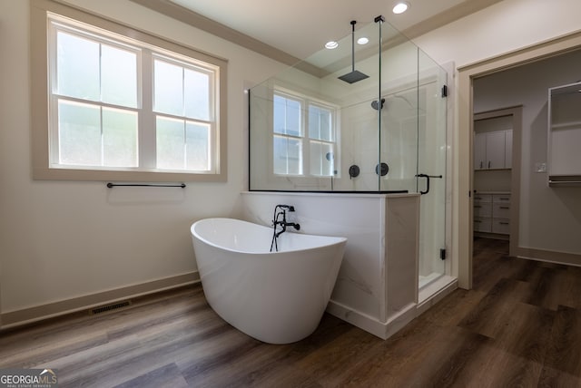 bathroom featuring a shower stall, recessed lighting, a freestanding tub, wood finished floors, and baseboards