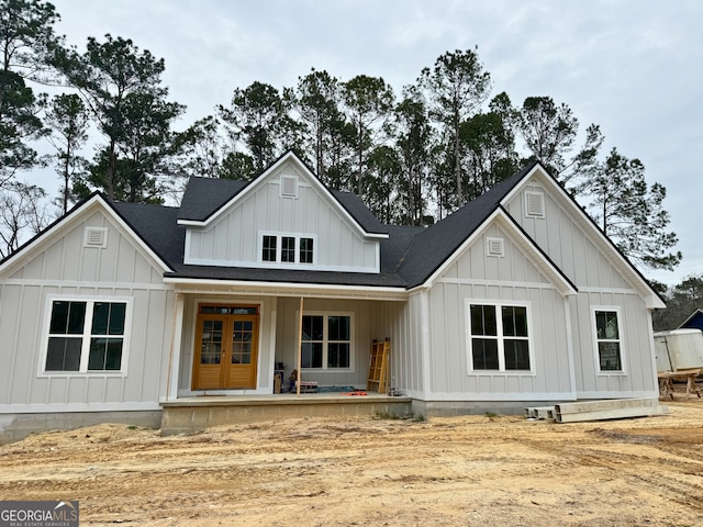 back of house with board and batten siding, french doors, and roof with shingles