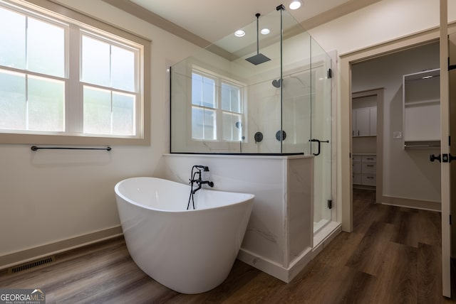 full bath featuring a shower stall, recessed lighting, a soaking tub, baseboards, and wood finished floors