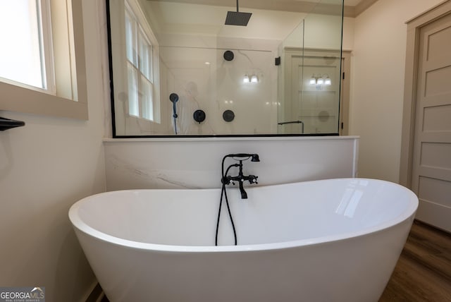 bathroom with a shower stall, wood finished floors, and a freestanding bath