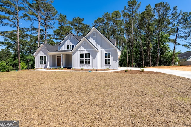 modern farmhouse style home with board and batten siding, a porch, and a front yard