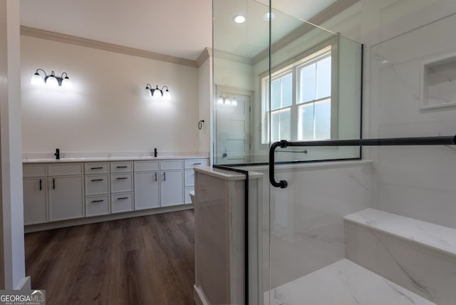bathroom with crown molding, a marble finish shower, wood finished floors, and double vanity