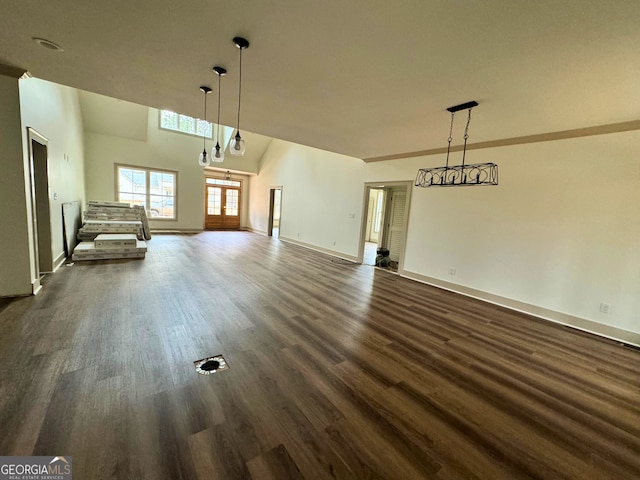 unfurnished living room featuring dark wood finished floors, baseboards, and a towering ceiling