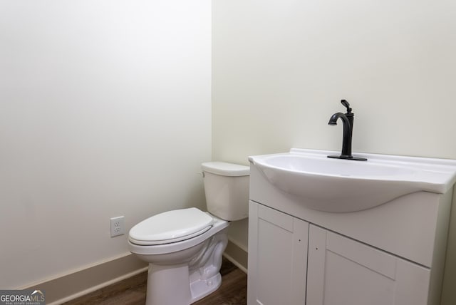 bathroom with wood finished floors, vanity, toilet, and baseboards