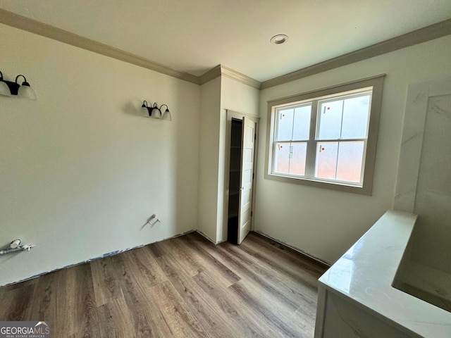 unfurnished bedroom featuring crown molding, a closet, and light wood finished floors