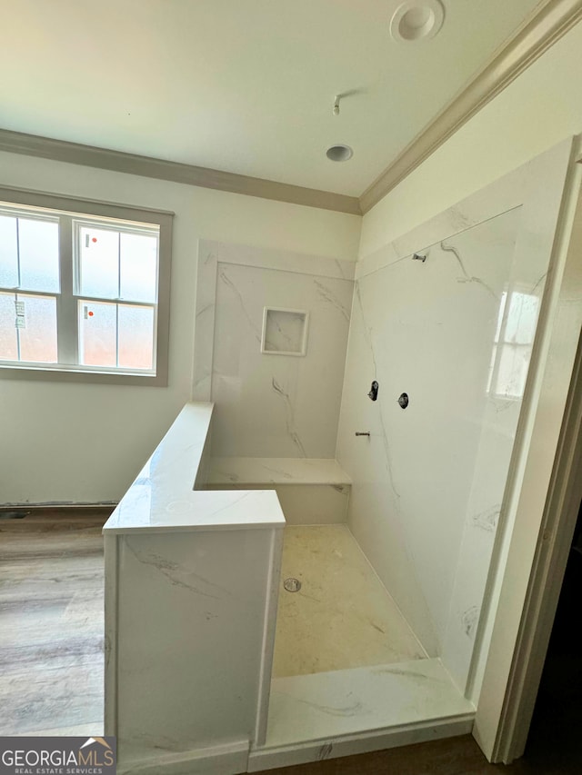 bathroom featuring a marble finish shower, crown molding, and wood finished floors