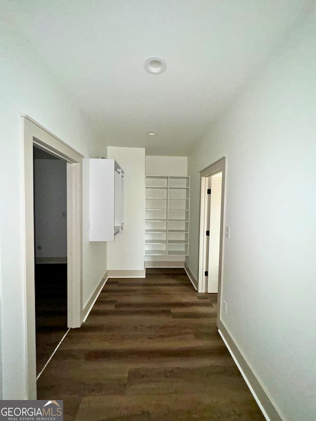 hall featuring baseboards and dark wood-type flooring