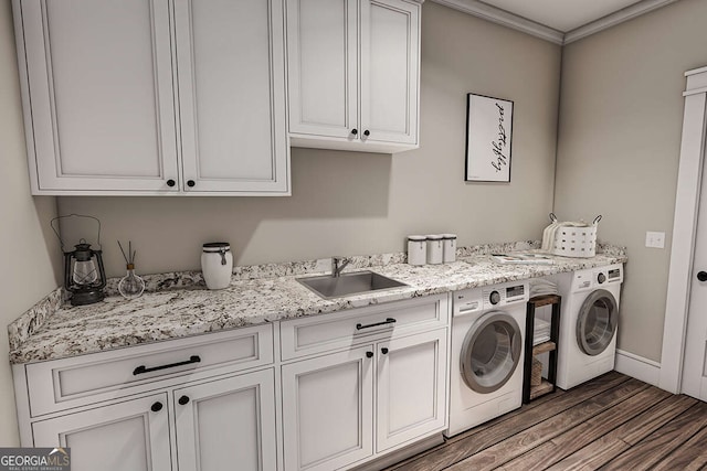 laundry area featuring a sink, washing machine and dryer, wood finished floors, cabinet space, and baseboards