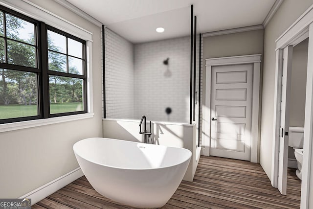 bathroom with wood finished floors, baseboards, a freestanding tub, crown molding, and toilet