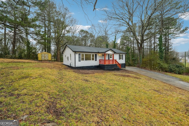 ranch-style house featuring a front yard and a storage shed