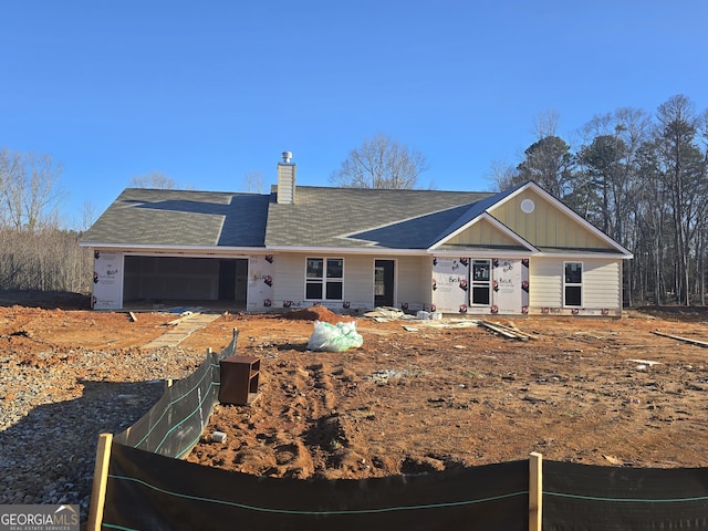 view of front facade featuring a garage, a chimney, and board and batten siding