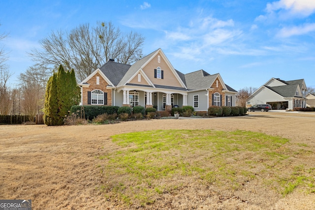 view of front of home with a porch, brick siding, and a front lawn