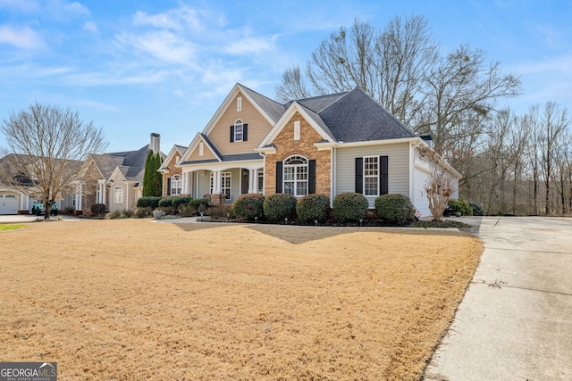 view of front of house with concrete driveway, covered porch, brick siding, and a shingled roof