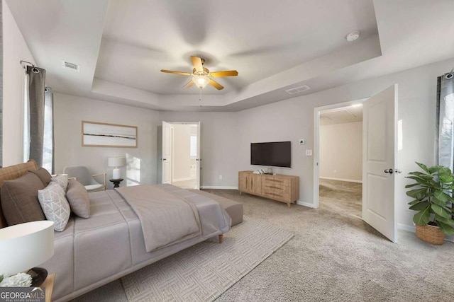 carpeted bedroom featuring ceiling fan and a raised ceiling