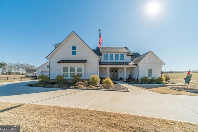 modern farmhouse style home with board and batten siding, a standing seam roof, fence, and concrete driveway