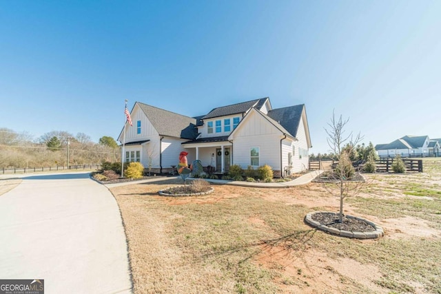 view of front of house with a front yard, fence, board and batten siding, and concrete driveway