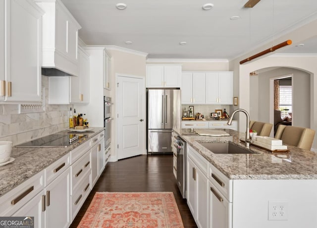 kitchen with white cabinetry, stainless steel appliances, a kitchen island with sink, and sink