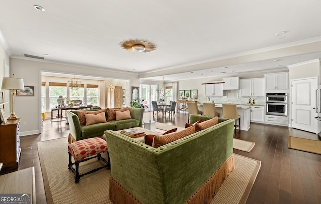 living room featuring crown molding, plenty of natural light, dark hardwood / wood-style floors, and a chandelier