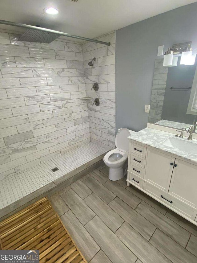 bathroom with vanity, tiled shower, and toilet