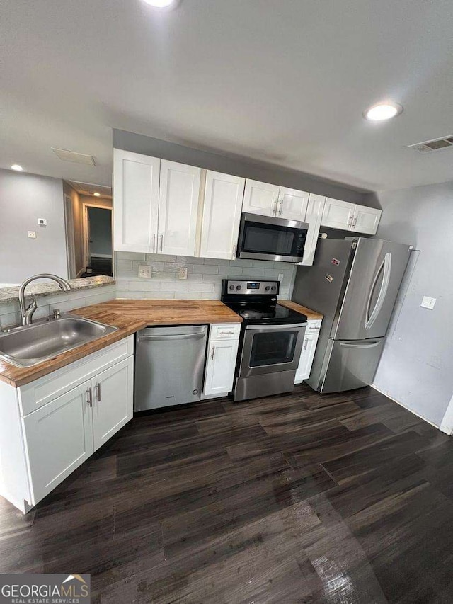 kitchen with appliances with stainless steel finishes, tasteful backsplash, white cabinetry, sink, and kitchen peninsula