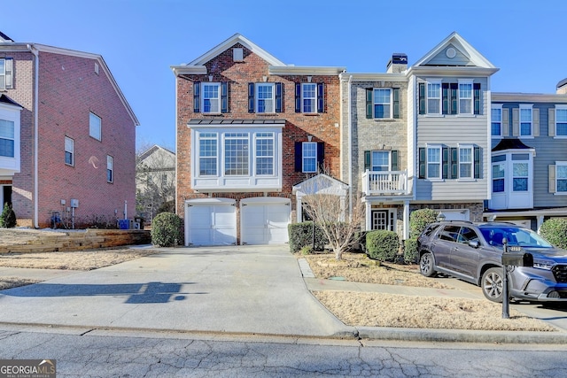 townhome / multi-family property with driveway, an attached garage, a chimney, and brick siding