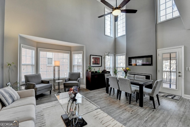 living room with baseboards, ceiling fan, and light wood finished floors