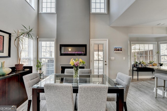 dining room featuring light wood-style floors and a high ceiling