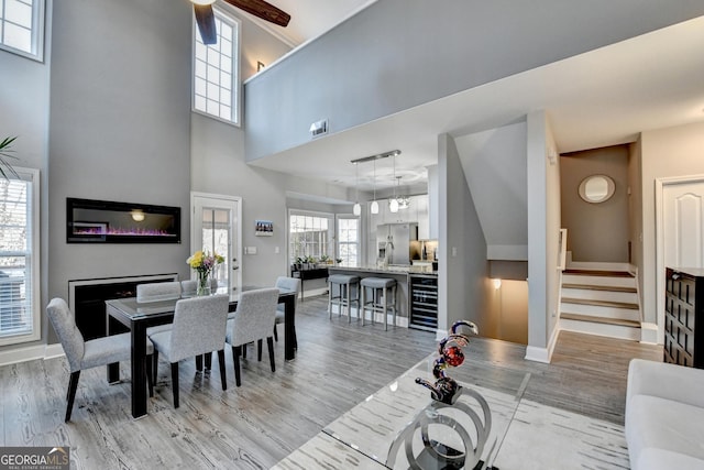 dining area with light wood-type flooring, wine cooler, stairway, and baseboards