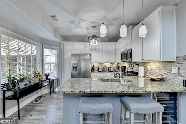 kitchen featuring decorative backsplash, decorative light fixtures, light stone countertops, stainless steel appliances, and white cabinetry