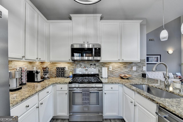 kitchen with decorative backsplash, appliances with stainless steel finishes, white cabinetry, pendant lighting, and a sink