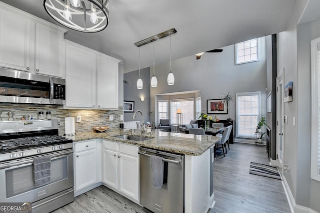 kitchen with a peninsula, appliances with stainless steel finishes, a sink, and white cabinets