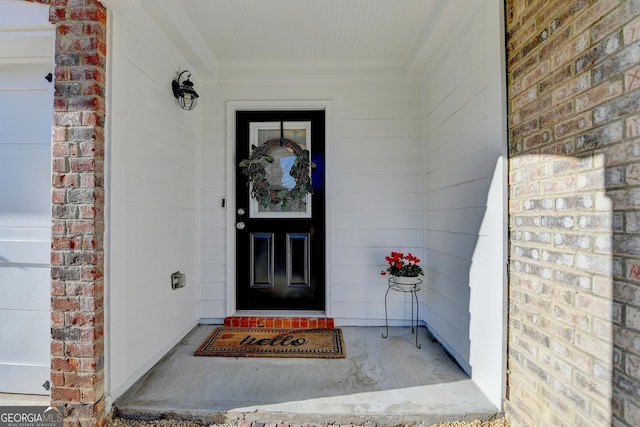 view of exterior entry with a garage and brick siding