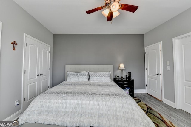 bedroom with a closet, baseboards, ceiling fan, and light wood finished floors