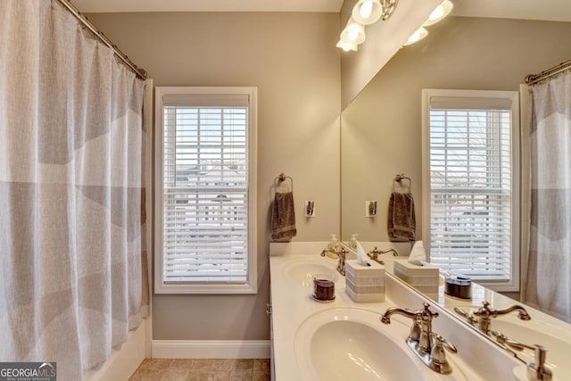 bathroom with tile patterned flooring, baseboards, a sink, and shower / tub combo with curtain