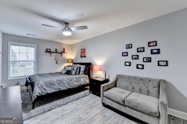 bedroom with light wood-style floors, ceiling fan, visible vents, and baseboards