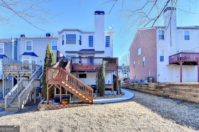 rear view of property with stairway, a chimney, and a wooden deck